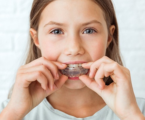 A girl putting on an athletic mouthguard