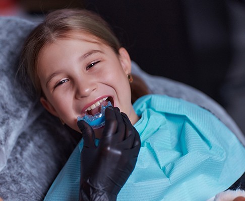 A girl getting an athletic mouthguard made by her dentist