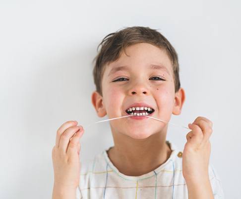 Little boy flossing his teeth
