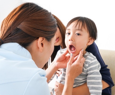 Dentist examining child after tooth extractions