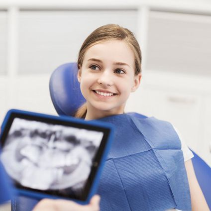 Young girl smiling in the dentist’s office after receiving tooth-colored fillings in Aspen Hill 