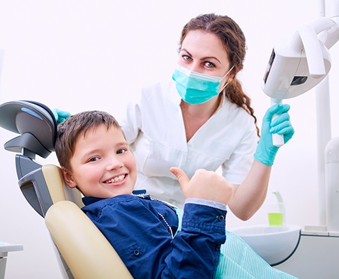 Young boy giving a thumbs up in the dentist’s chair and smiling