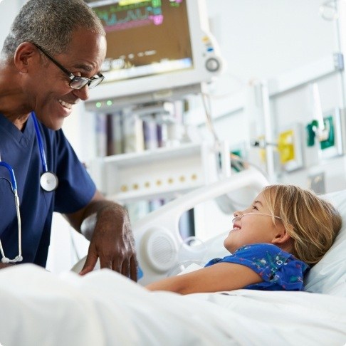 Doctor talking to child in hospital bed