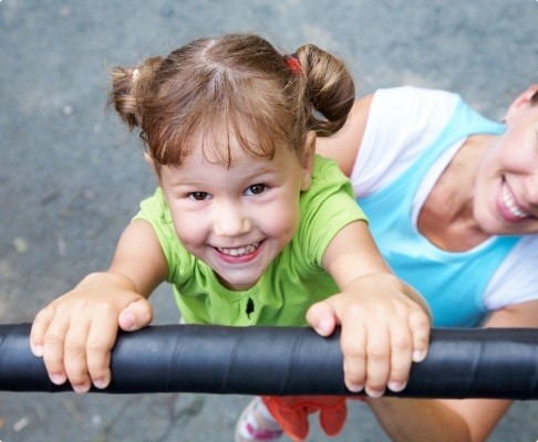 Mother on playground with smiling child after dentistry for toddlers