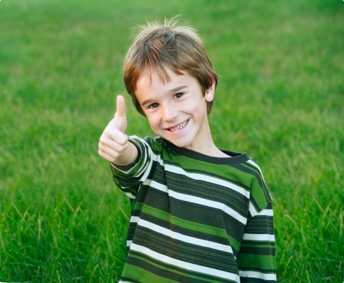 Child giving thumbs up after pediatric dentistry visit