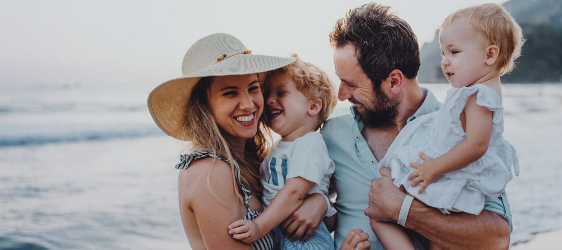 Mother father and two young children laughing on the beach