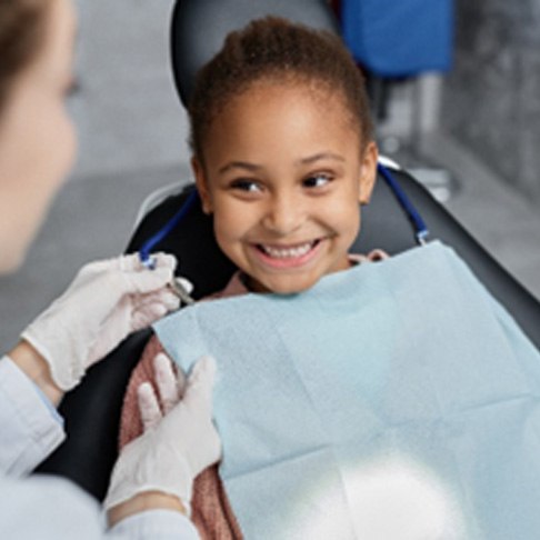 Young girl smiling at pediatric dentist during dental checkup