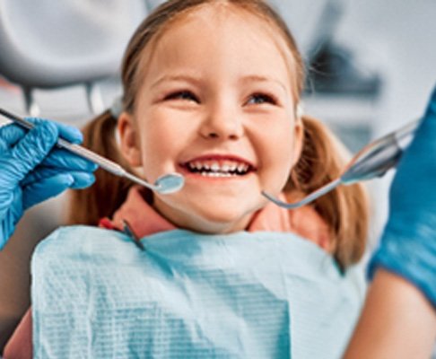 Closeup of child smiling during dental checkup with pediatric dentist