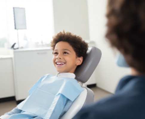 Child smiling while sitting in pediatric dentist's treatment chair