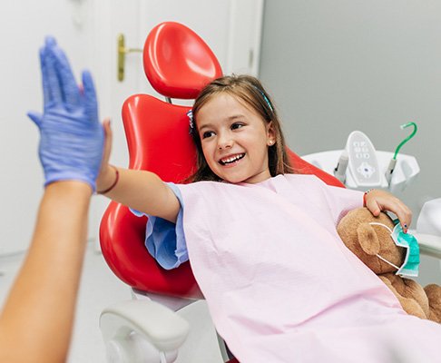 Child smiling while giving dentist high five