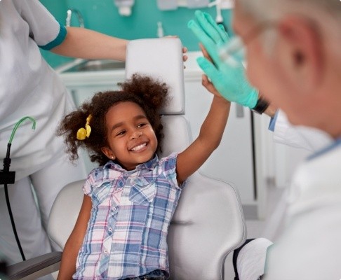 Child giving dentist a high five during oral health risk assessment visit