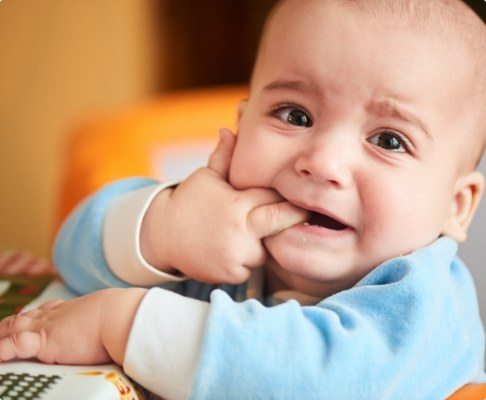 Teething baby chewing fingers