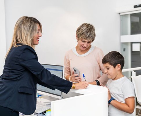 Dental team member helping mother and child at front desk