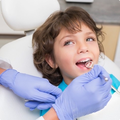 Dentist examining child's smile during restorative dentistry visit