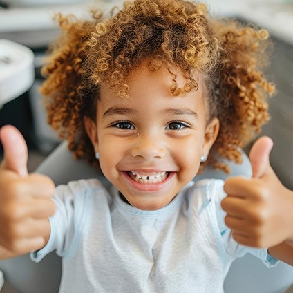 Young patient giving two thumbs up and smiling after sedation dentistry in Aspen Hill
