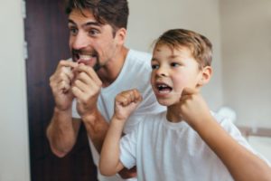 father teaching son how to floss 