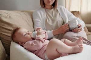 Baby drinking bottle while lying on bed