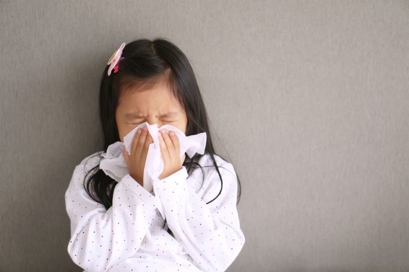 A child with good oral health sneezes into a tissue