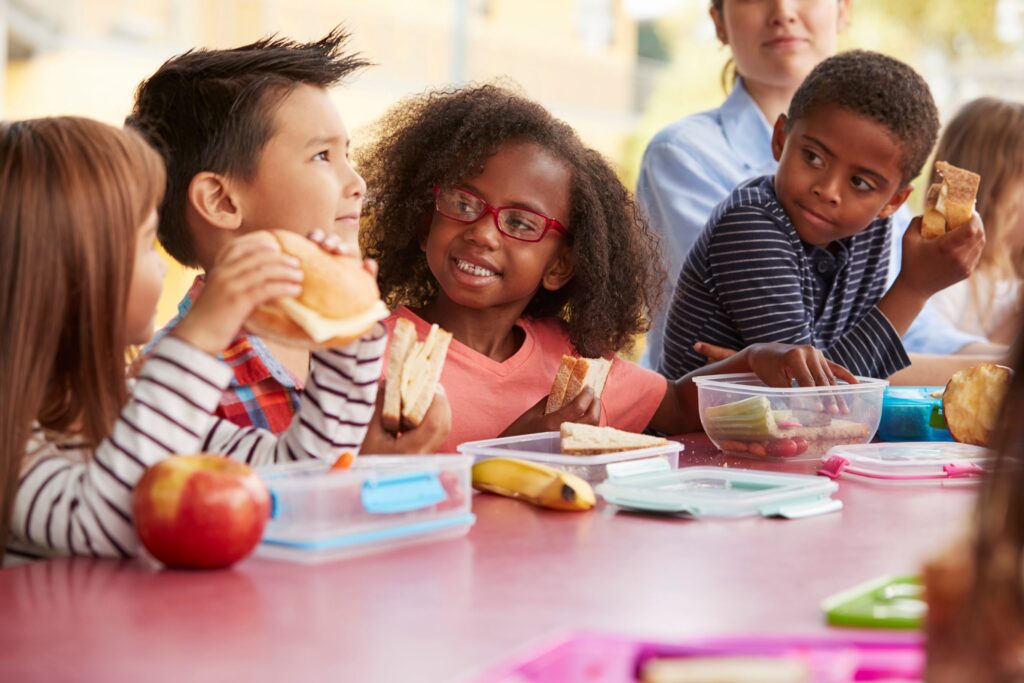 Diverse group of kids at red table eating lunch